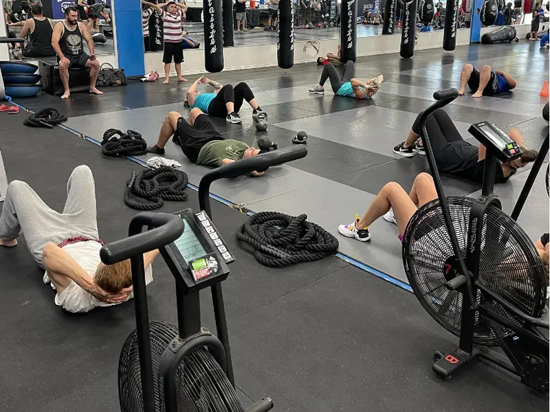 A HIIT class works through core exercises between air bikes and battle ropes.